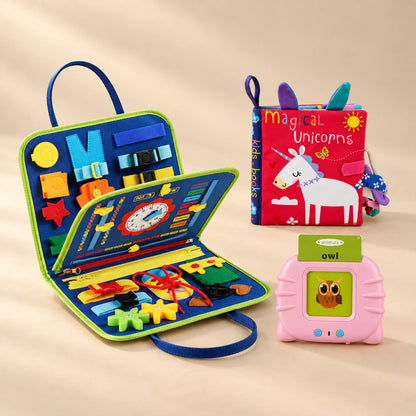Grandparent Gift Bundle with a dinosaur blue busy board, pink talking flashcard reader and Magical Unicorns sensory book on a beige studio surface.
